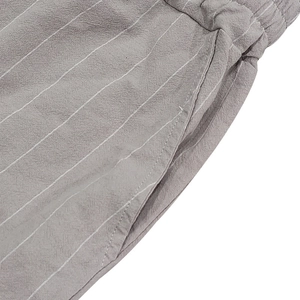 Detail of grey striped linen shorts featuring elastic waistband and side pockets