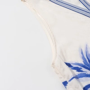Close-up of tropical leaf print fabric with blue and white striped trim on the seam