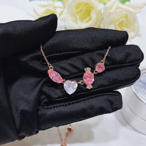 Detail of rose gold necklace with heart-shaped pink crystals held in black gloves