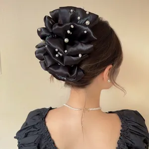 Dettaglio del fermaglio per capelli in tulle nero con perle indossato sulla nuca