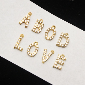 Close-up of gold-plated A-Z letter pendants featuring cubic zirconia micro-inlay details