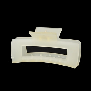 Détail d'une pince à cheveux rectangulaire crème mate sur fond noir contrasté