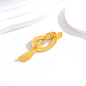 Broche nœud dorée avec finition texturée et fermoir épingle sur fond blanc épuré