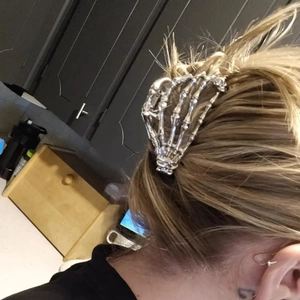 Dettaglio del fermaglio per capelli a mano di scheletro in metallo argento su capelli biondi