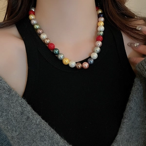 Close-up of colorful pearl necklace with mixed beads on a model wearing casual layers
