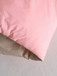 Detailopname van de roze en khaki omkeerbare bodywarmer met zachte gewatteerde stof