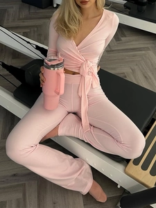 Ensemble de yoga rose avec haut à manches longues col V et pantalon évasé sur pilates