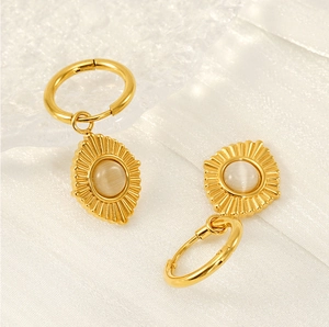 Detail of 18K gold stainless steel earrings with cat eye stones on white silk texture
