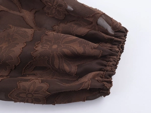 Détail de la manche en tulle marron foncé avec broderie florale et poignet élastique