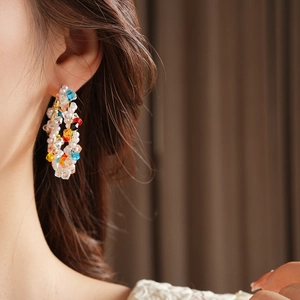 Primo piano di una modella che indossa orecchini a cerchio con perline colorate e perle