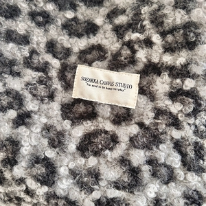 Close-up of leopard print faux shearling fabric with a rectangular canvas brand label