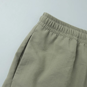 Detail of elastic waistband and side pockets on casual olive green cotton linen trousers