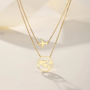 Detail of gold layered necklace featuring airplane and world map globe pendants
