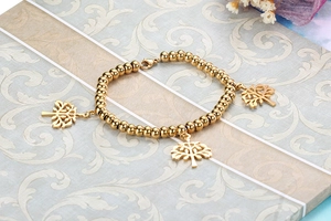Détail du bracelet à billes dorées avec pendentifs arbre de vie et fermoir mousqueton