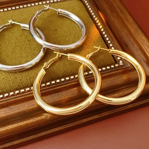 Polished gold and silver hoop earrings on green velvet lining within a vintage frame