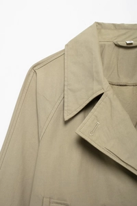 Close-up of khaki trench coat collar and shoulder detail with neat stitching and button