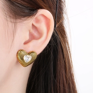 Macro detail of a 18k gold heart stud earring featuring radial texture and a center crystal
