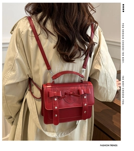 Model wearing a vintage red leather crossbody bag with heart and bow detail