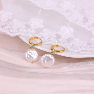 Detailed close-up of sterling silver pearl earrings with gold hoop and turquoise bead accents