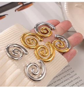 Vue détaillée de boucles d'oreilles spirales dorées et argentées sur maille blanche