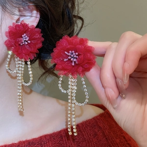 Detail of red floral earrings with long crystal tassels shown on a model
