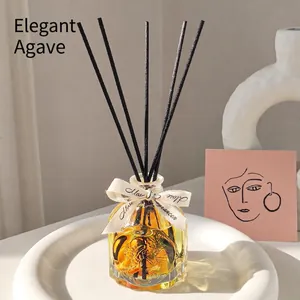 Minimalist agave reed diffuser set with glass bottle and black reeds on a white stand