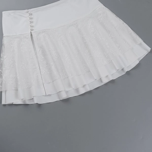 Detailed close-up of the white lace trim and side button design on the mini skirt