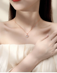 Detail of rose gold heart pendant necklace with moissanite center on female model