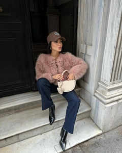 Dettaglio di una giacca in ecopelliccia rosa abbinata a cappello marrone e borsa beige