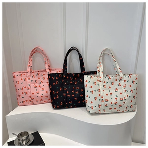 Detailed view of quilted cherry print tote bags in pink, black, and beige cream colors