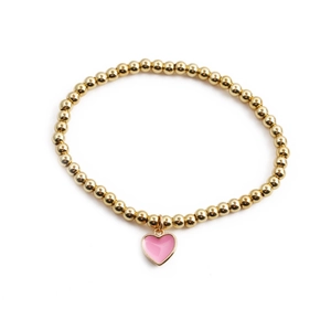 Fashionable gold beaded elastic bracelet with a pink enamel heart pendant on white background