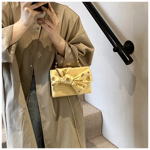 Detailed view of luxury gold satin evening clutch with large bow and jeweled embellishments