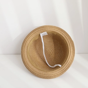 Detail view of the inner paper straw hat showing adjustable elastic wind strap and sweatband