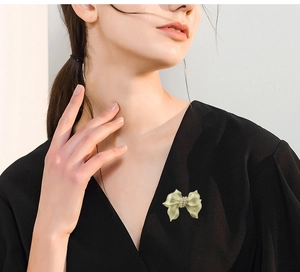 Detail of elegant bow brooch with pearls on black V-neck knit sweater outfit