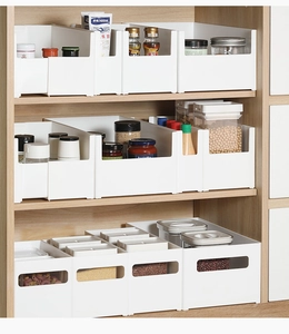 Close-up of white stackable storage bins organized in a minimalist wooden cabinet shelf