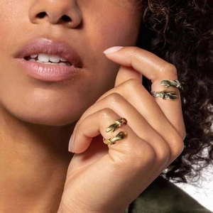 Detailed view of two hugging hands rings in gold and silver finish on a finger