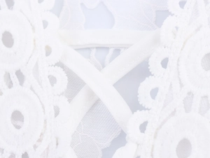 Close-up of white floral lace detail and crisscross lace-up design on the long dress