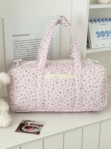 Dettaglio borsa da viaggio trapuntata rosa con motivi floreali e fiocchi decorativi