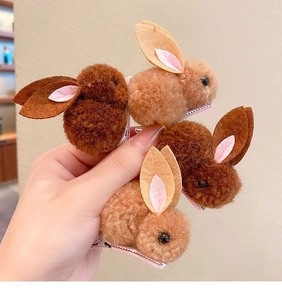 Détail de deux pinces à cheveux lapin en peluche marron foncé et clair en main