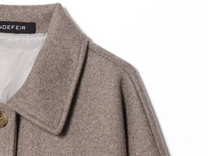 Detailed view of camel wool blend coat featuring sharp collar and premium fabric texture