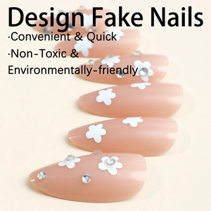 Almond nude press-on nails with white flower patterns and rhinestones on beige background