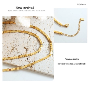 Close-up of golden square bead necklace featuring an 18K stamp and lobster clasp