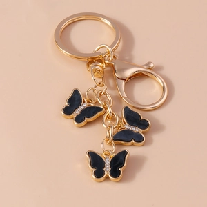 Golden butterfly keychain with black enamel drips and sparkling white rhinestones