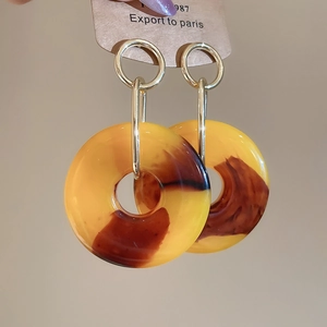 Detail of amber resin drop earrings featuring tortoise patterns and golden metal links