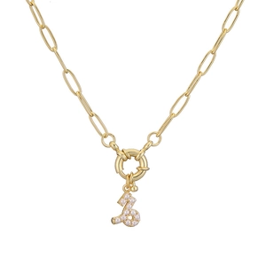 Detailed macro view of gold paperclip chain necklace with pearl-inlaid zodiac pendant