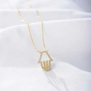 Sparkling gold S925 silver Hamsa hand necklace with pavé cubic zirconia on white silk