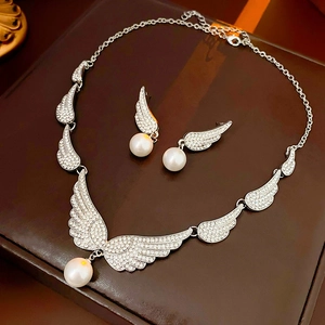 Close-up of wing-shaped jewelry set with silver rhinestones and white pearls