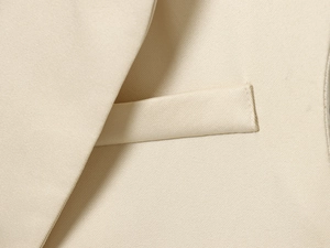 Détail du revers beige et des coutures de poche précises sur une veste tissée chic