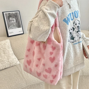 Detail of plush pink tote bag with heart patterns and soft faux fur texture