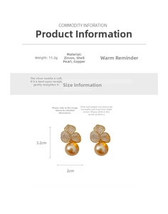 Detail view of gold flower earrings with white zircon inlay and pearl drop